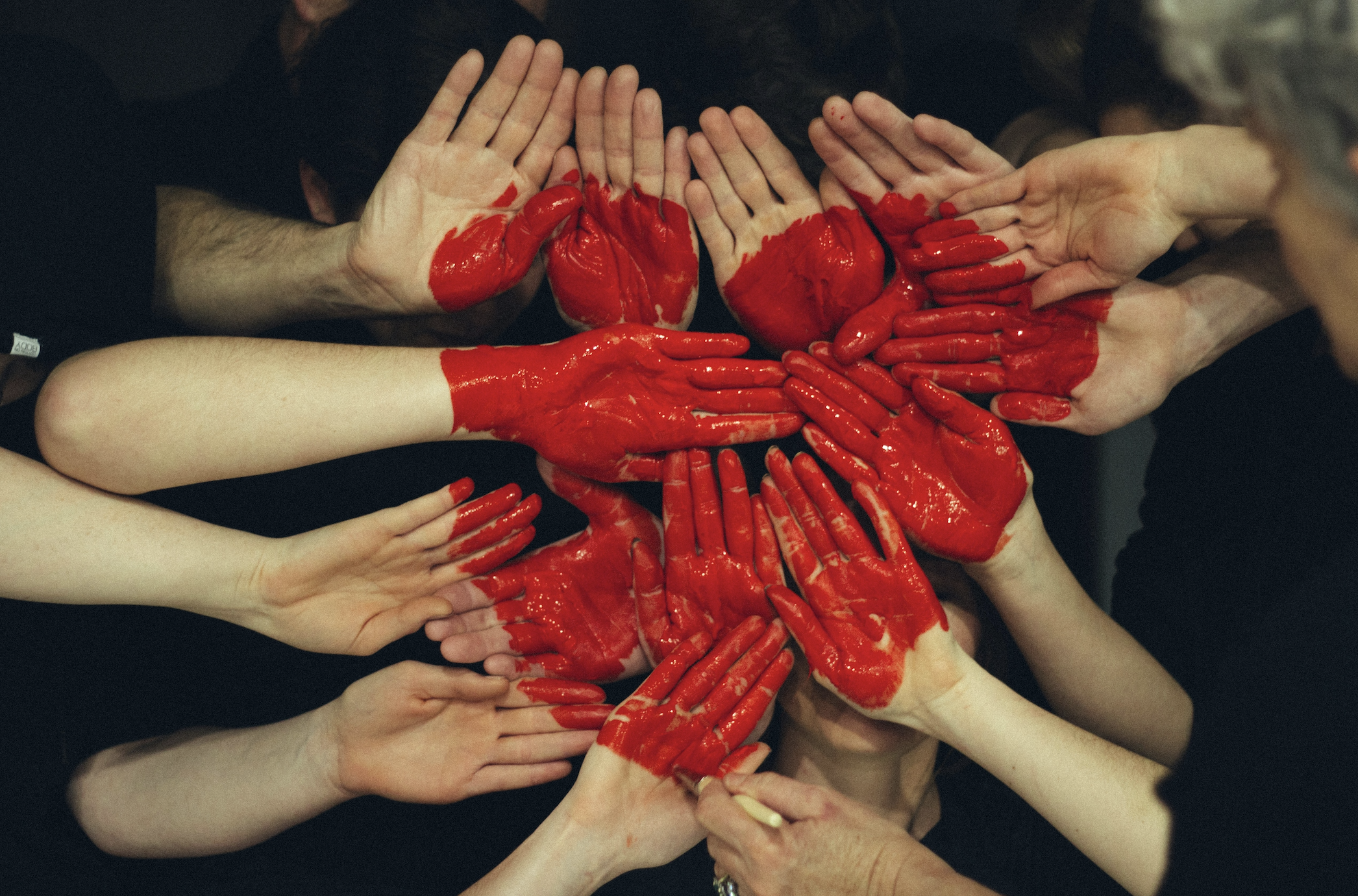 Hands painted in red forming hearts