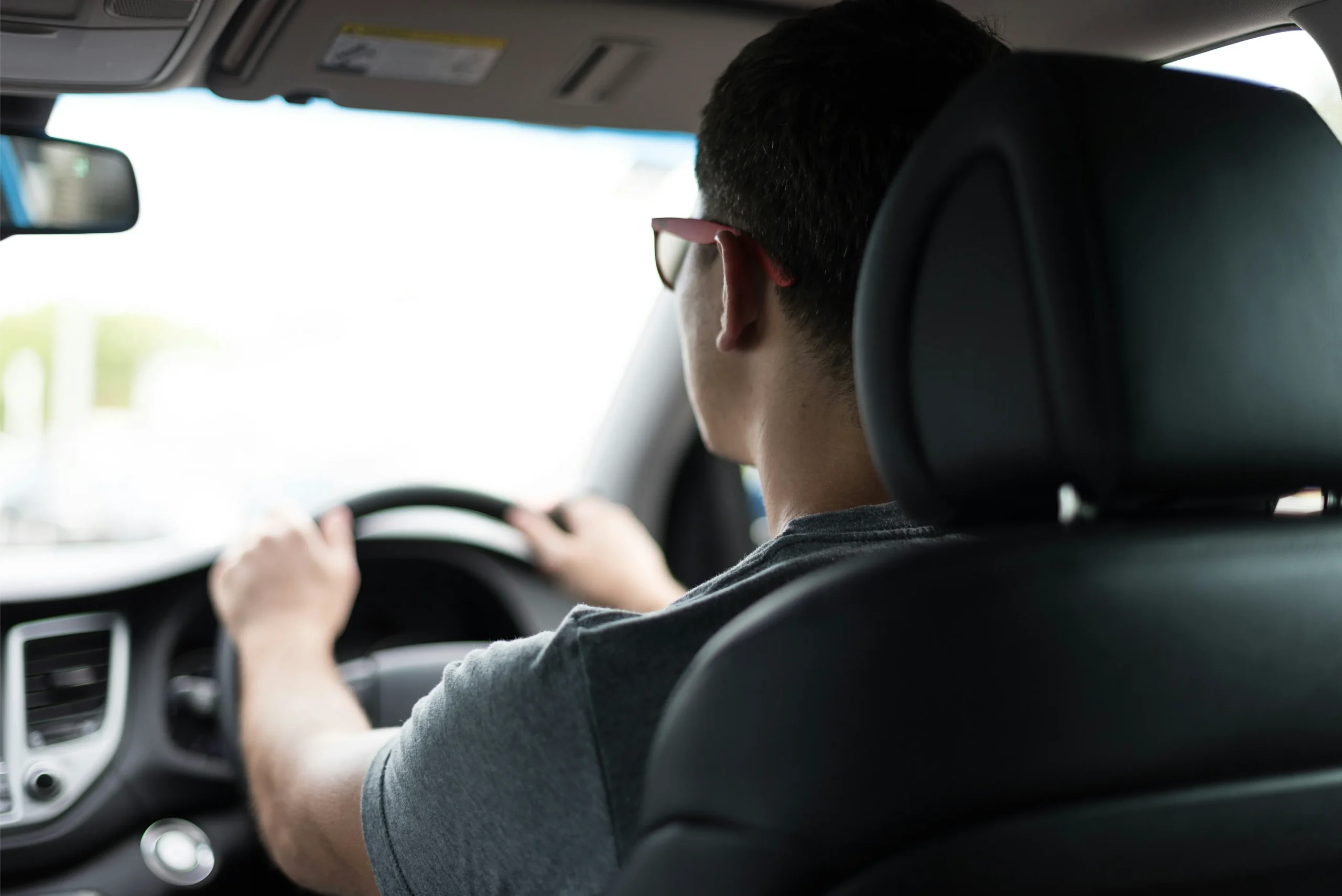 Guy in glasses driving a car.