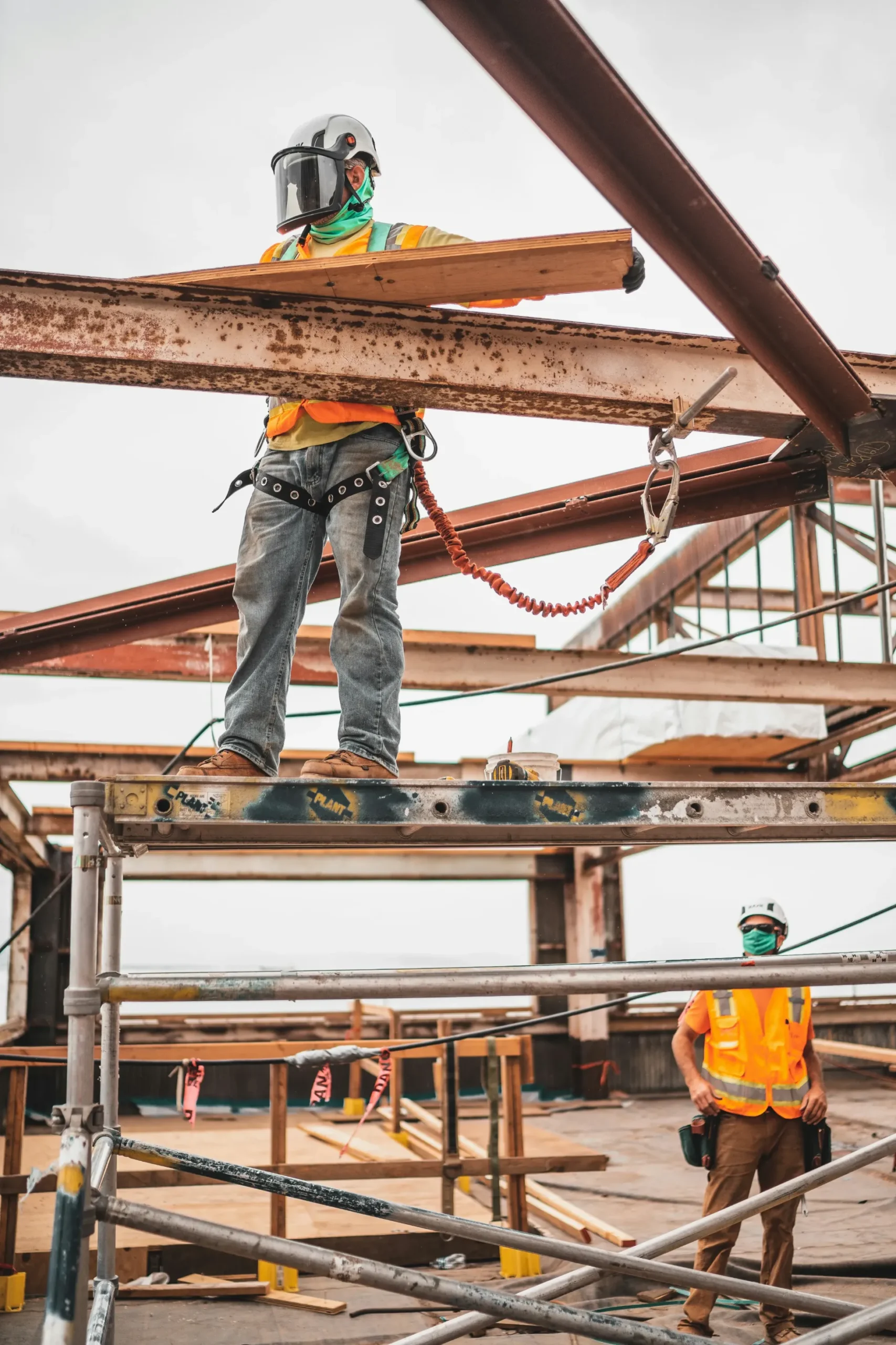 Two guys in orange vests is working hard on a construction site.